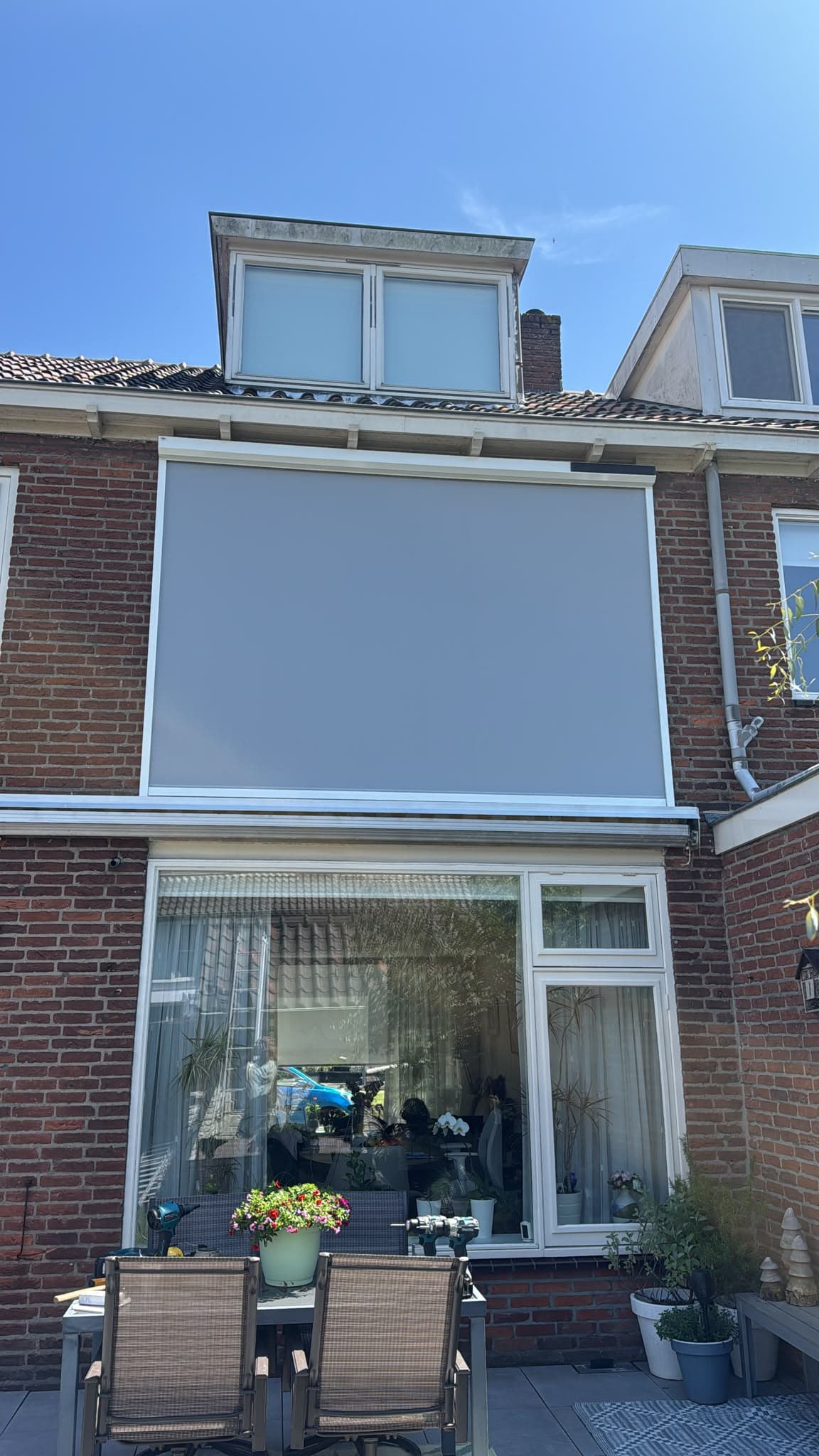 Geïnstalleerd zonnescherm boven een terras aan de achterzijde van een woning
